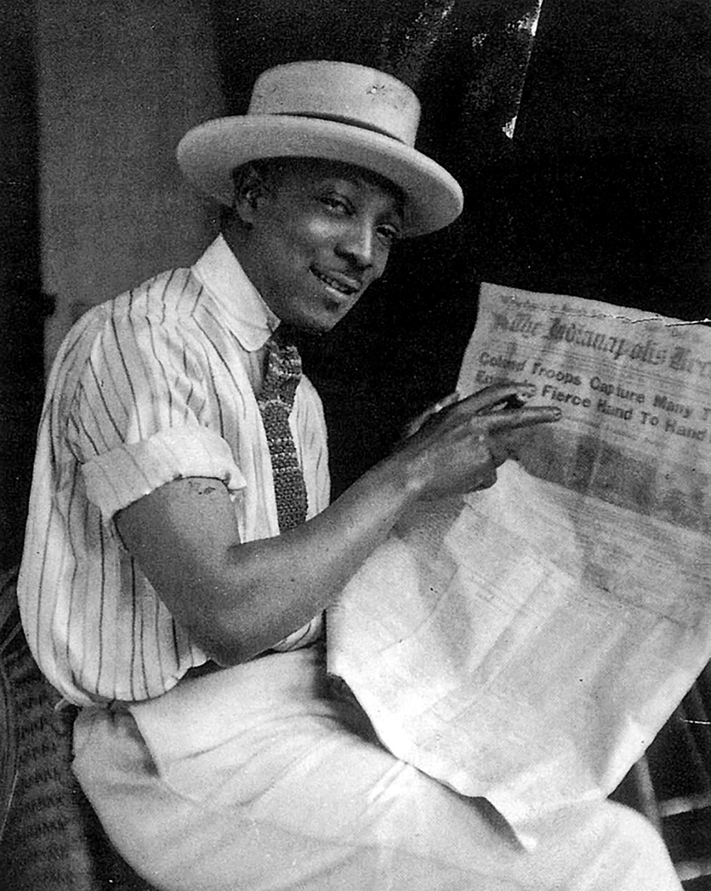 Self-portrait of James Van Der Zee, 1918, reading a newspaper account of Black troops in the First World War.
