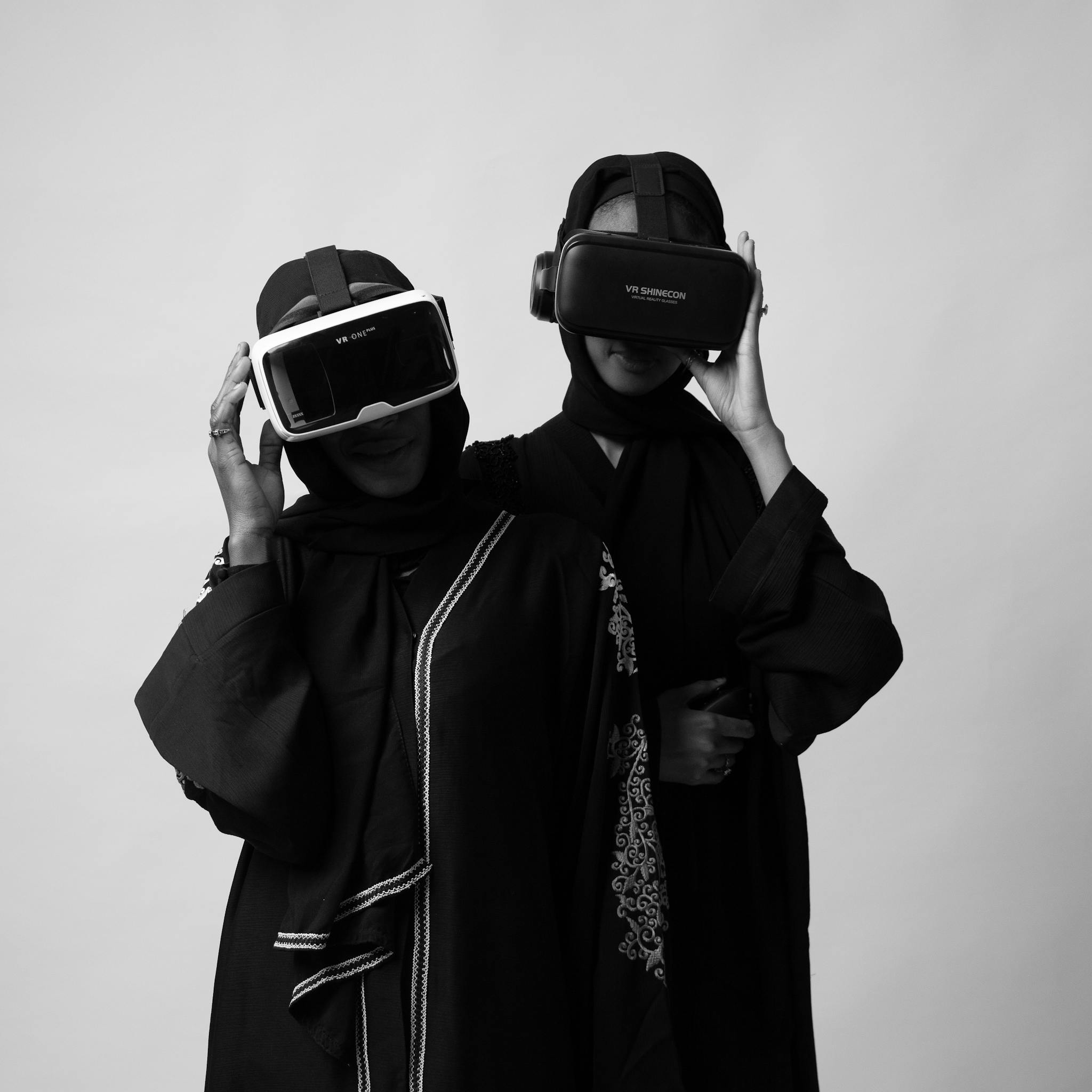 Two women in traditional attire experience virtual reality using VR headsets in a studio setting.