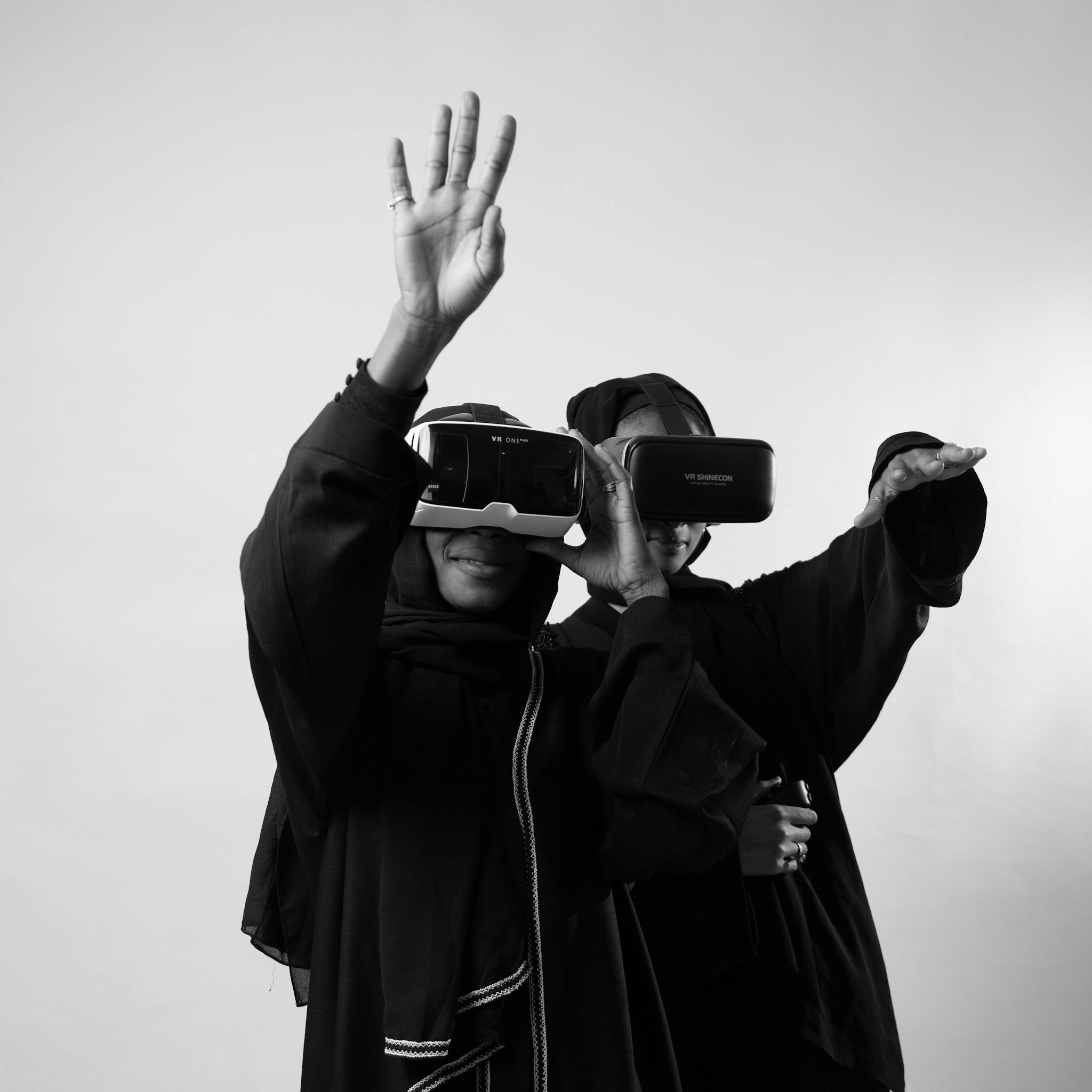 Two women wearing VR headsets explore virtual reality, captured in monochrome.